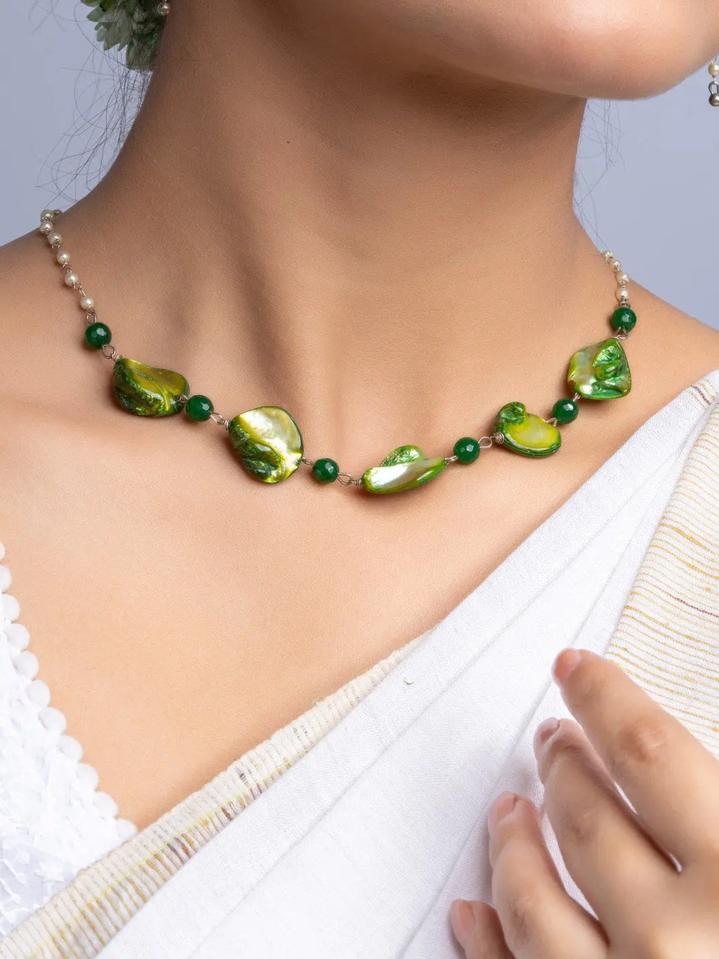 Handmade mother of pearl necklace set with green iridescent beads worn on a model's neck