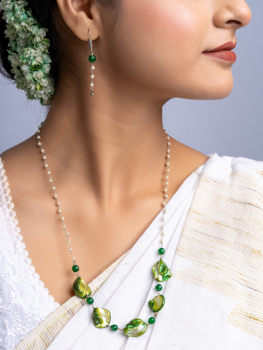 Handmade mother of pearl necklace set with green beads worn by woman in white traditional attire