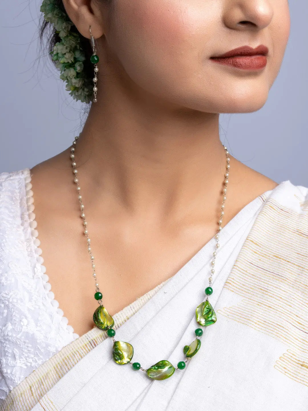 Handmade mother of pearl necklace set with green accents worn with traditional white saree