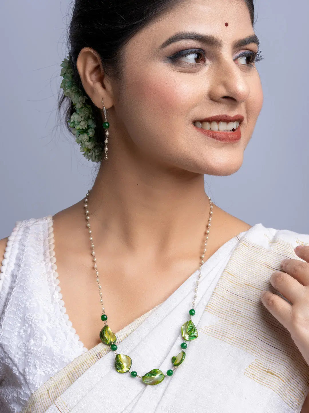 Elegant mother of pearl necklace set with green beads worn by woman in white saree, handmade jewelry by LOOK AND ADORN