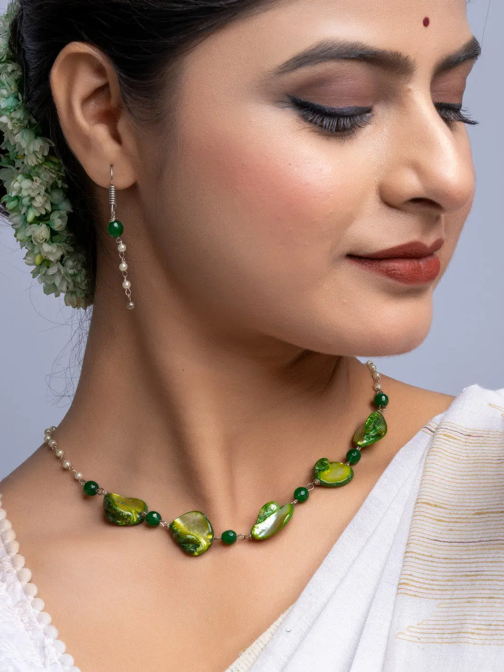 Handmade mother of pearl necklace set with green and pearl beads worn by woman with traditional attire