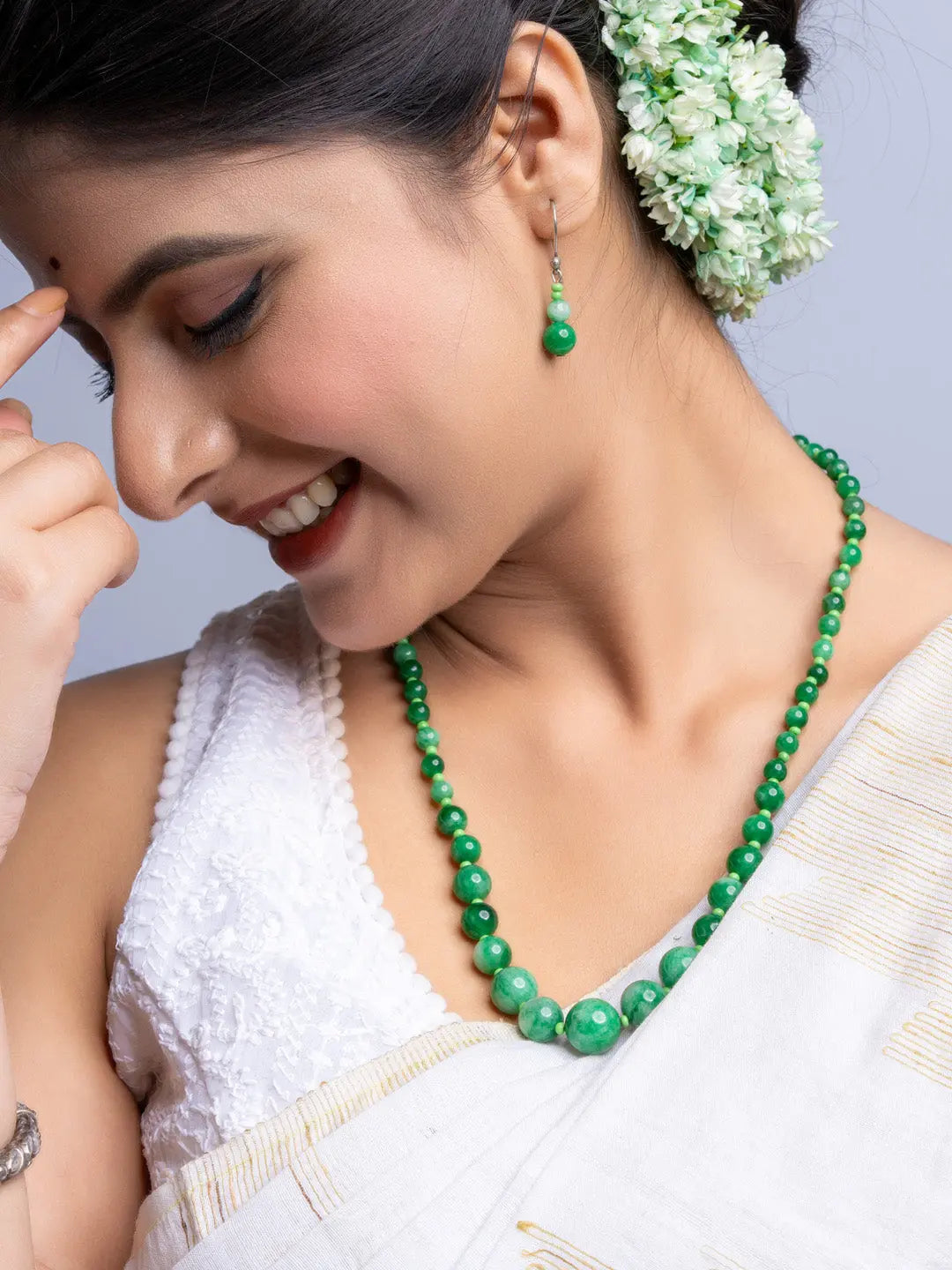 Woman wearing handmade green onyx necklace and matching earrings with white traditional attire