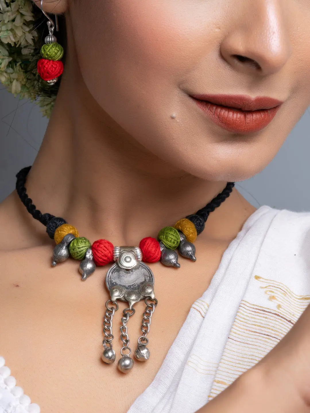 Close-up of a woman wearing a colorful afghani necklace set with red, green, and yellow beads and silver pendant