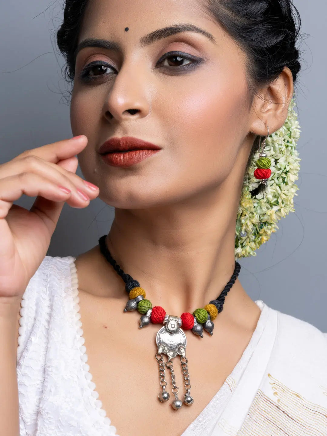 Afghani necklace set with colorful beads and silver pendant worn by woman with traditional attire