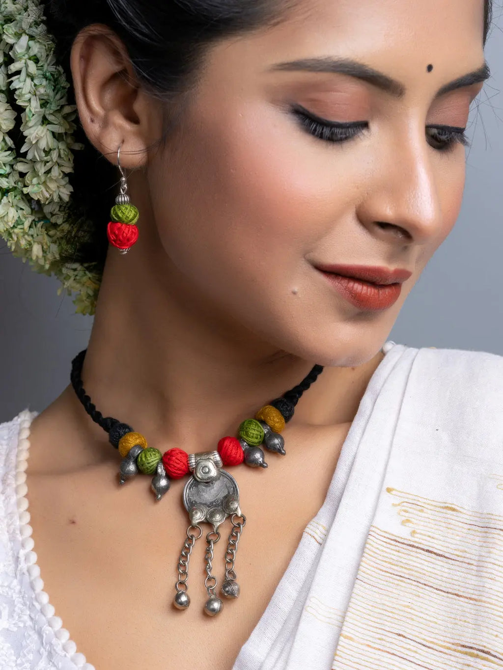 Close-up of woman wearing colorful Afghani necklace set with red, green, and yellow beads and silver pendant
