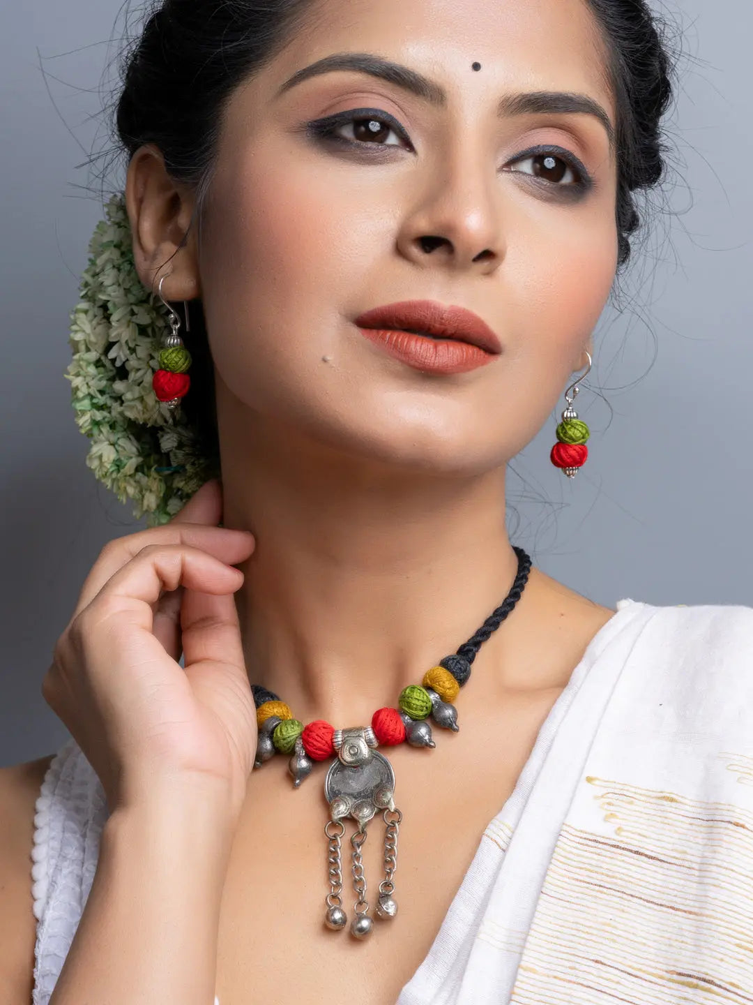 Elegant afghani necklace set with colorful beads and silver pendant worn by woman with floral hair accessory