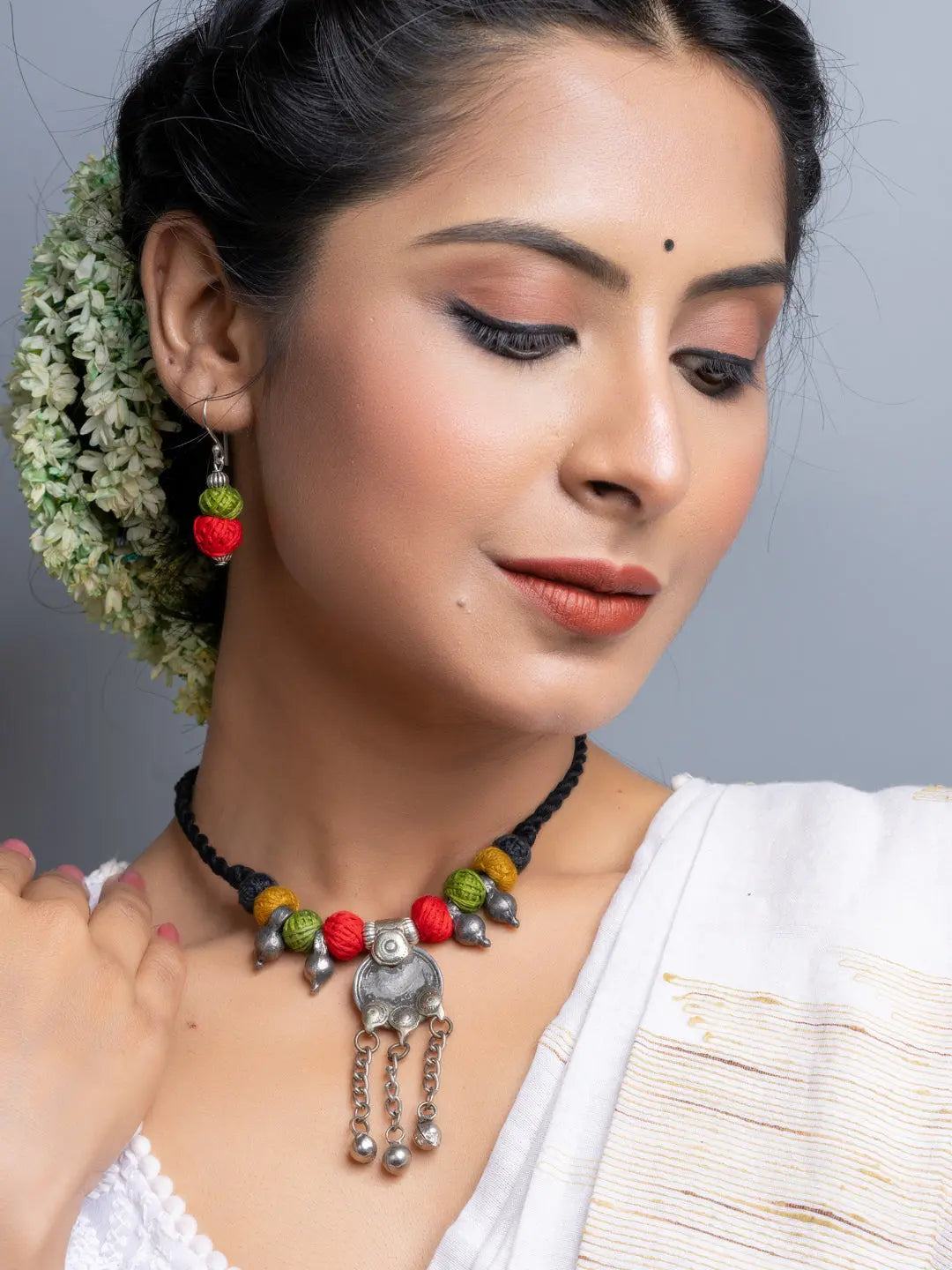 Woman wearing a colorful afghani necklace set with traditional silver pendant and matching earrings