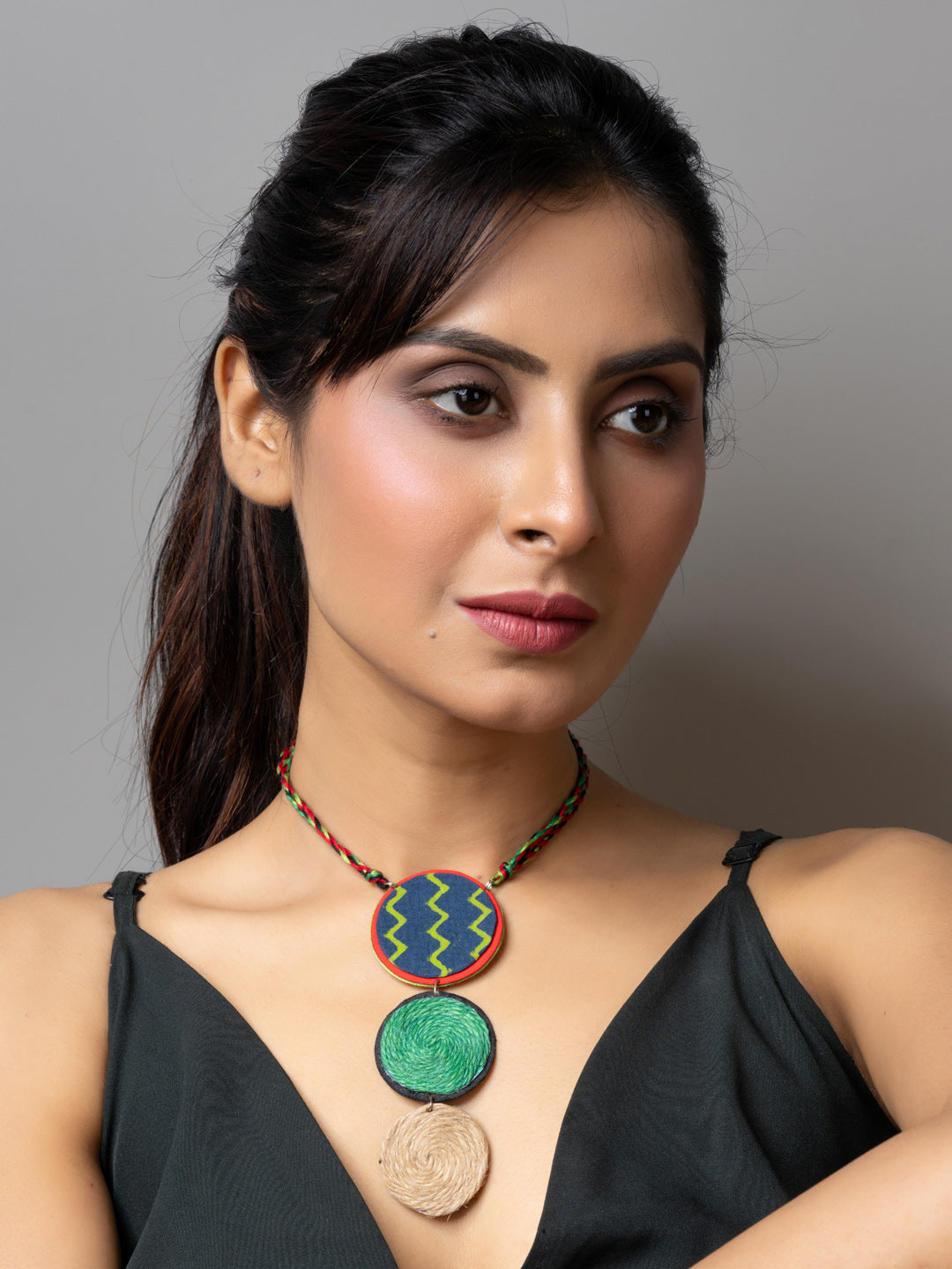 Handmade jute necklace with colorful round pendants worn by woman in black sleeveless top