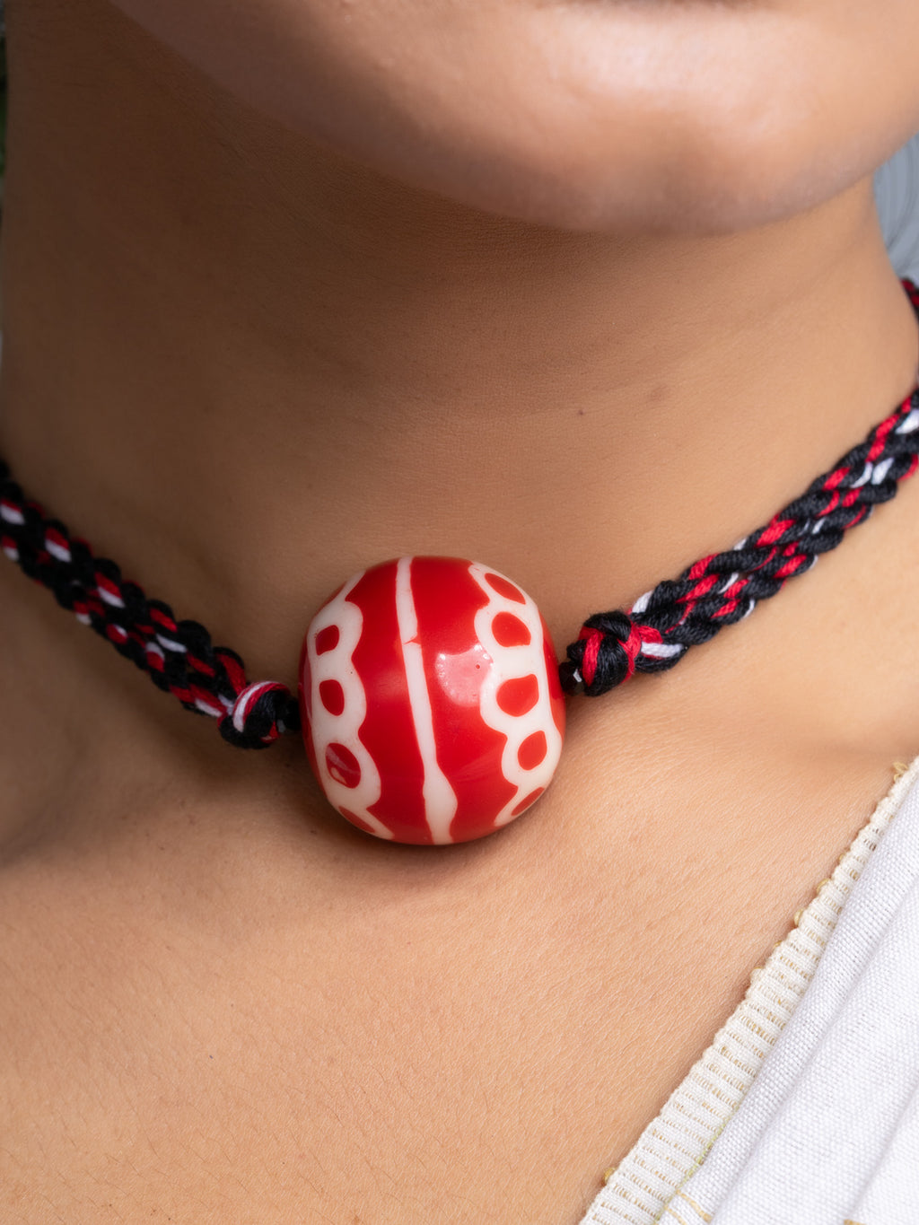 Handmade necklace set featuring a large red and white bead on braided black and red cord