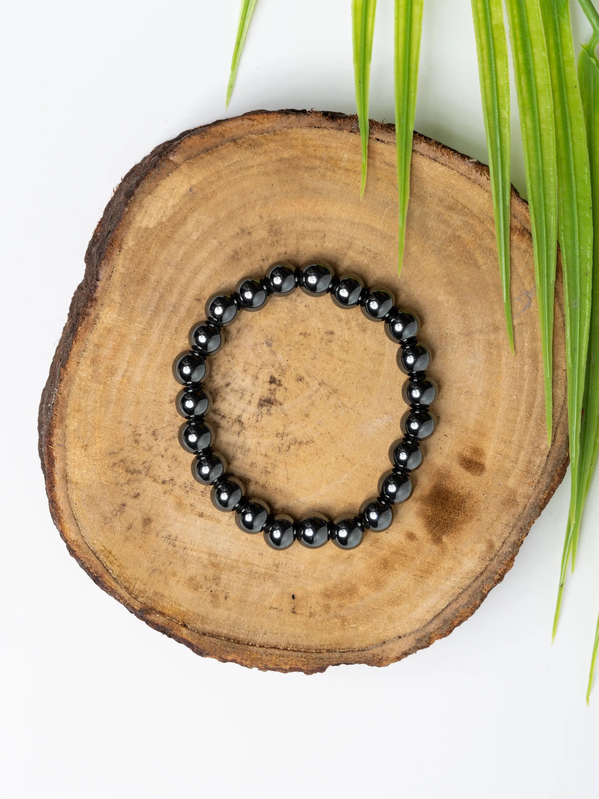 Hematite bracelet featuring polished black beads on a natural wood display
