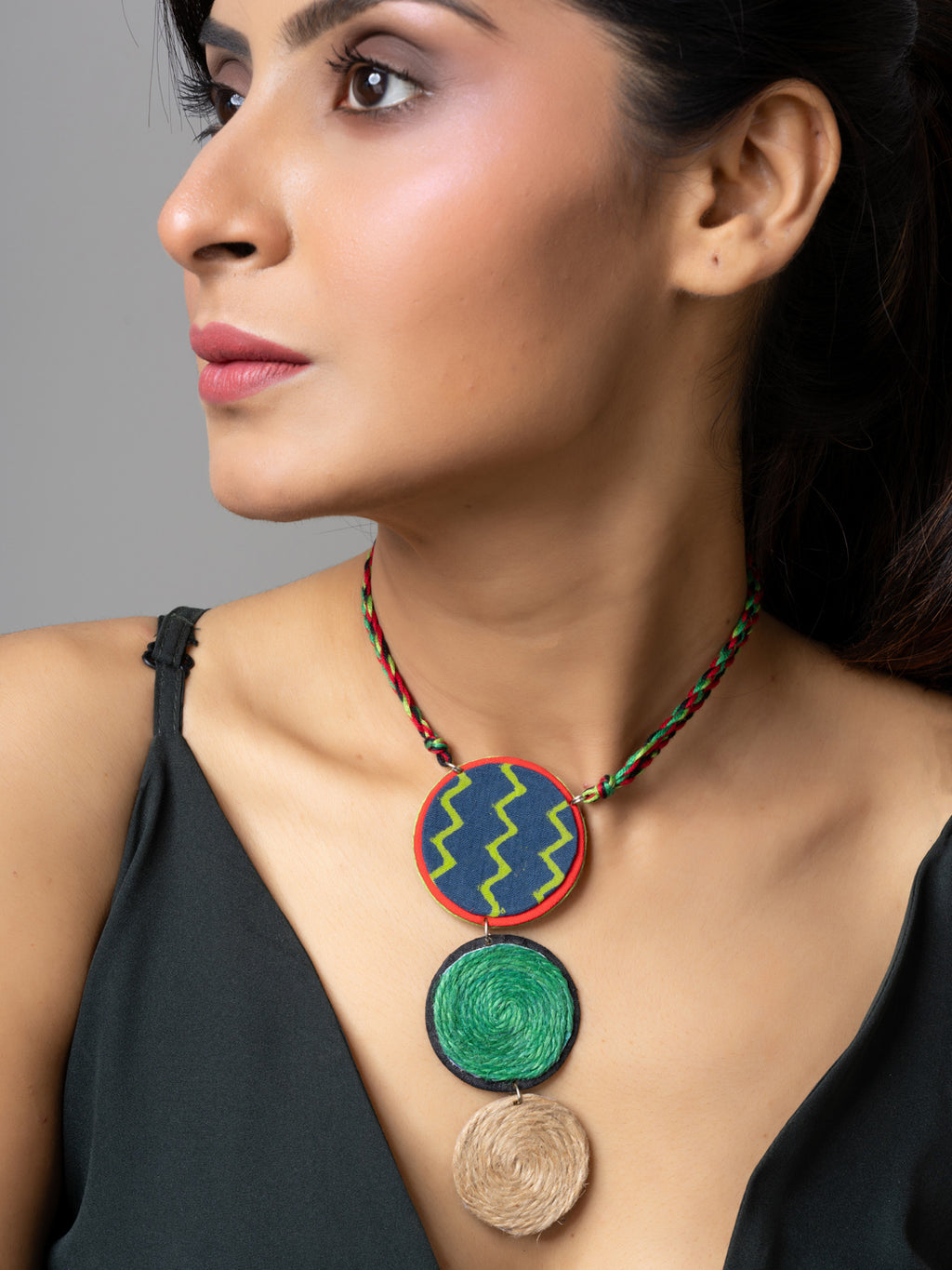 Handmade jute necklace with colorful circular pendants worn by woman in black top