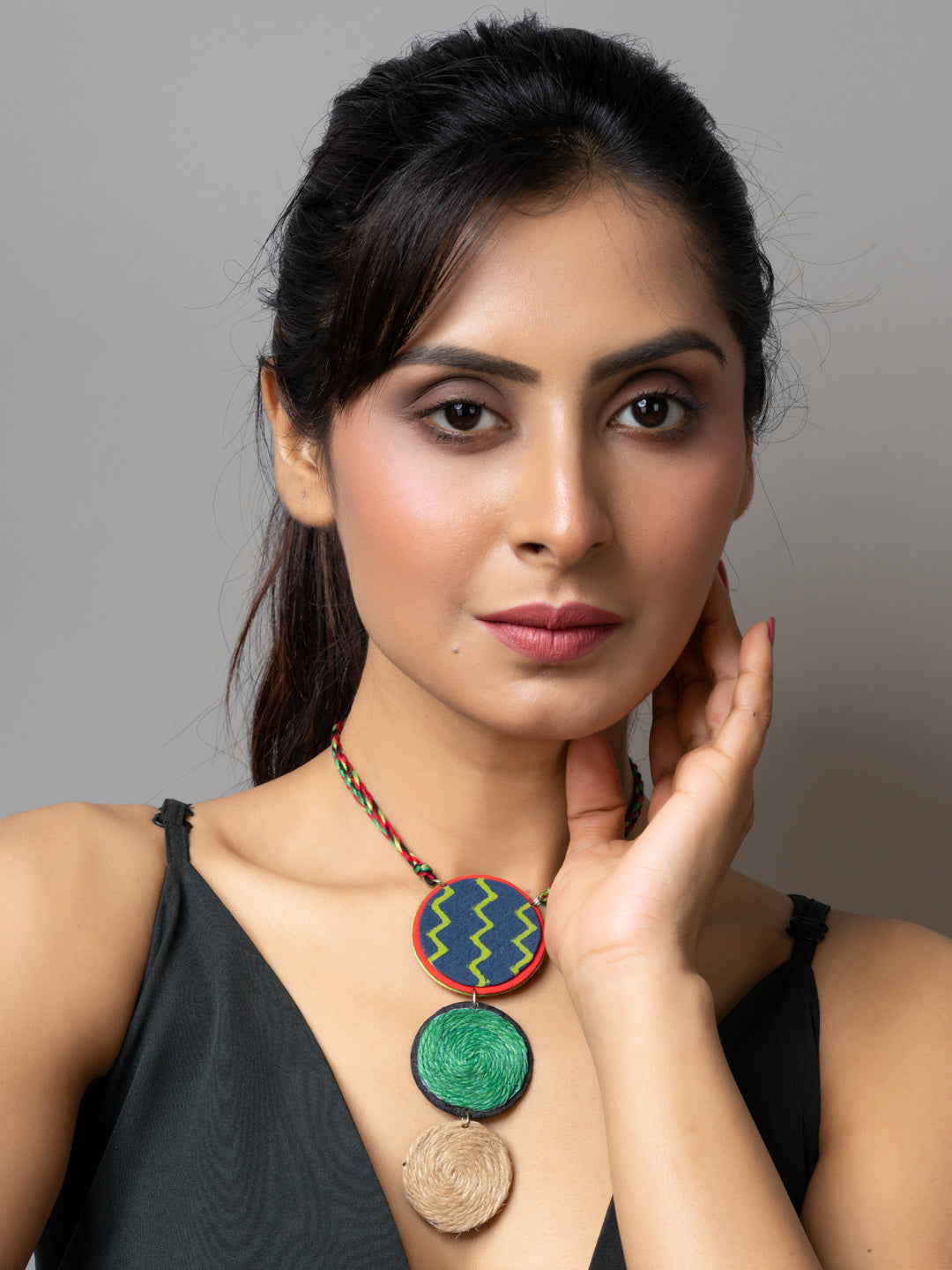 Handmade jute necklace with colorful round pendants worn by woman in black top