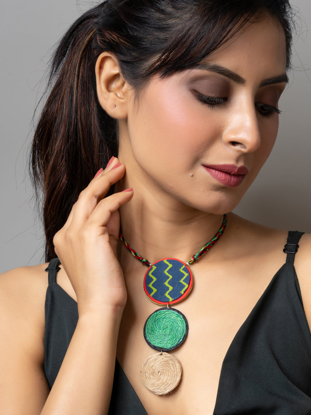 Woman wearing handmade jute necklace with colorful round pendants and braided cord