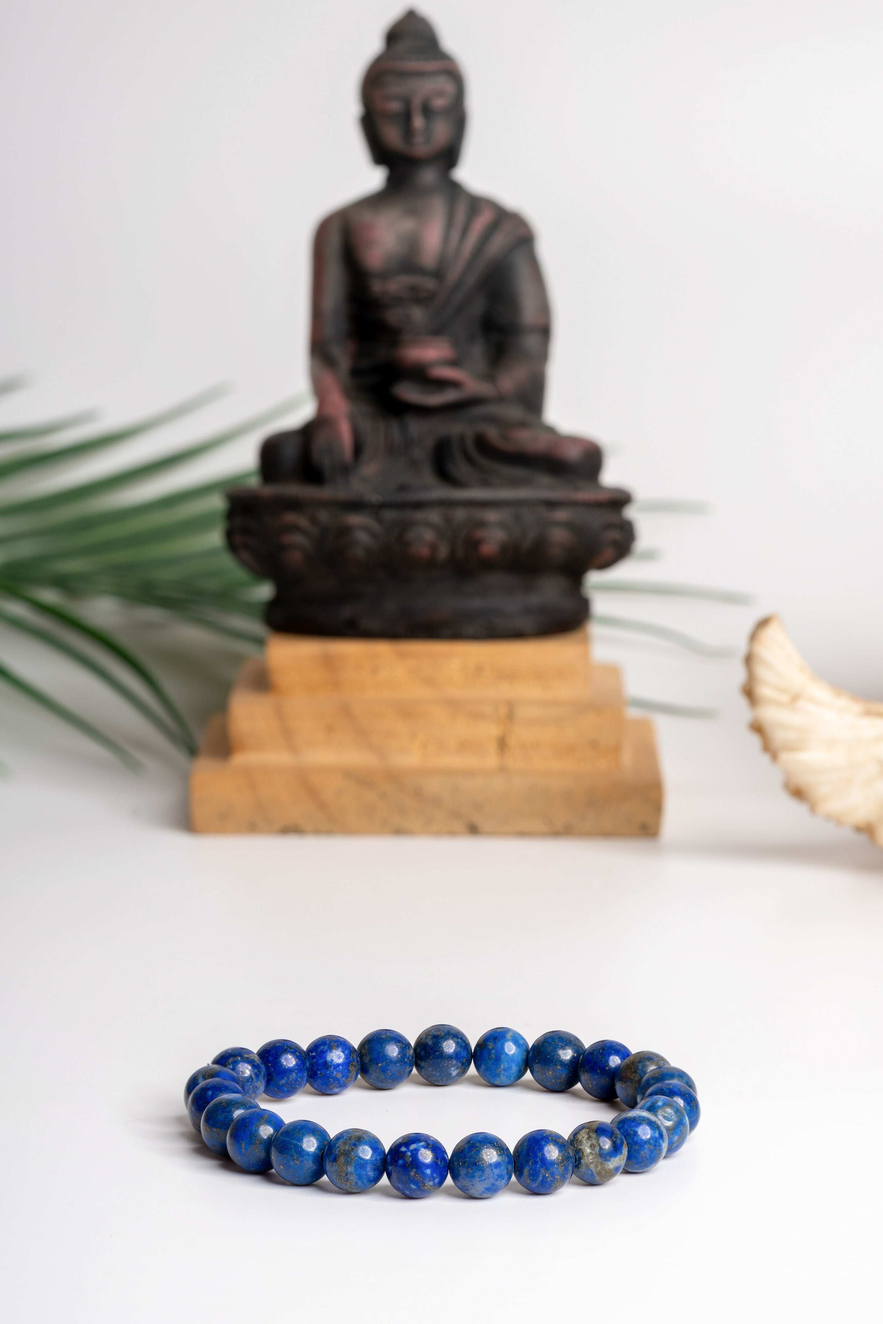 Lapis lazuli bracelet with vibrant blue beads set against a serene Buddha statue background