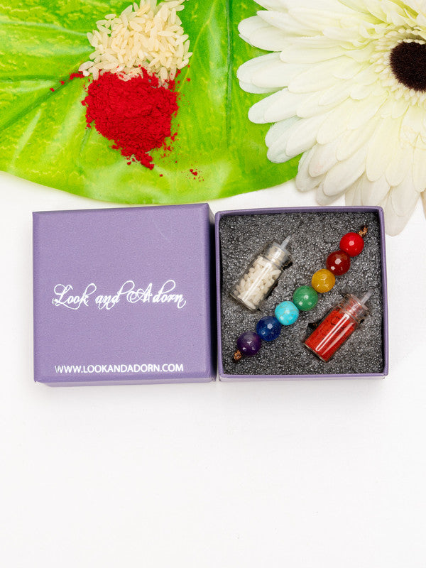 7 chakra rakhi with multicolored beads and small glass bottles in a purple Look and Adorn gift box
