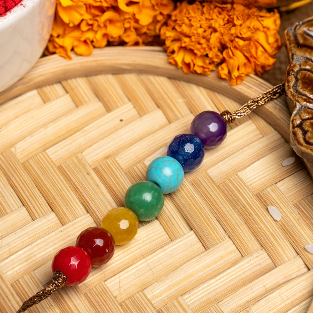 LOOK AND ADORN 7 chakra rakhi with colorful gemstone beads on a woven bamboo mat