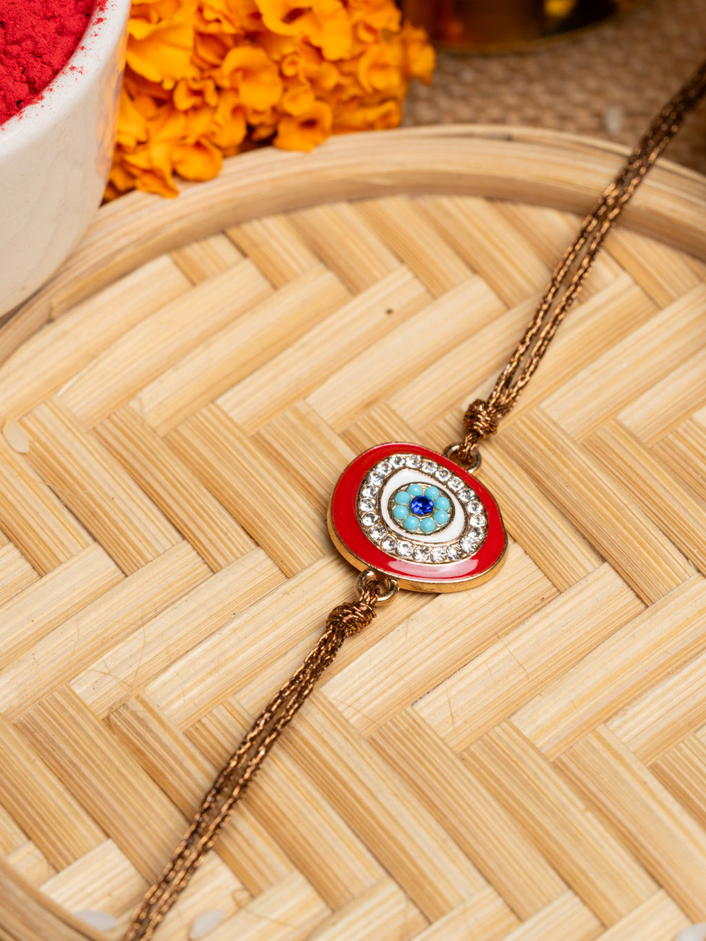 LOOK AND ADORN evil eye rakhi with blue eye centerpiece and decorative crystals on golden thread