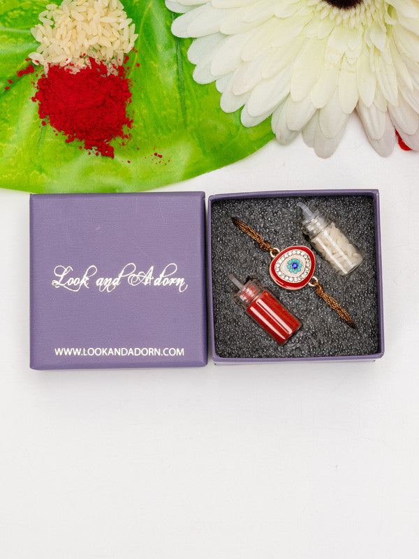Evil eye rakhi in a purple Look and Adorn gift box with red and white powders and flower decoration