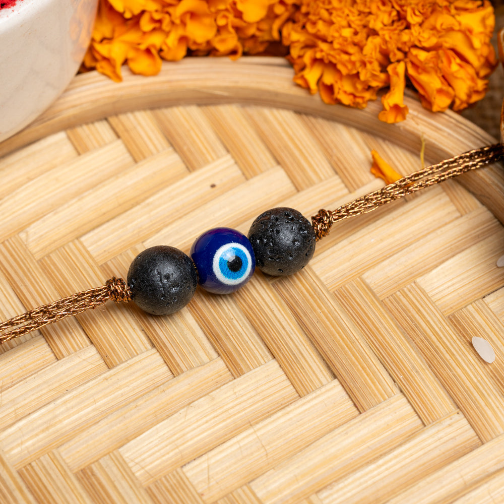 LOOK AND ADORN evil eye rakhi with blue bead and black stones on golden thread