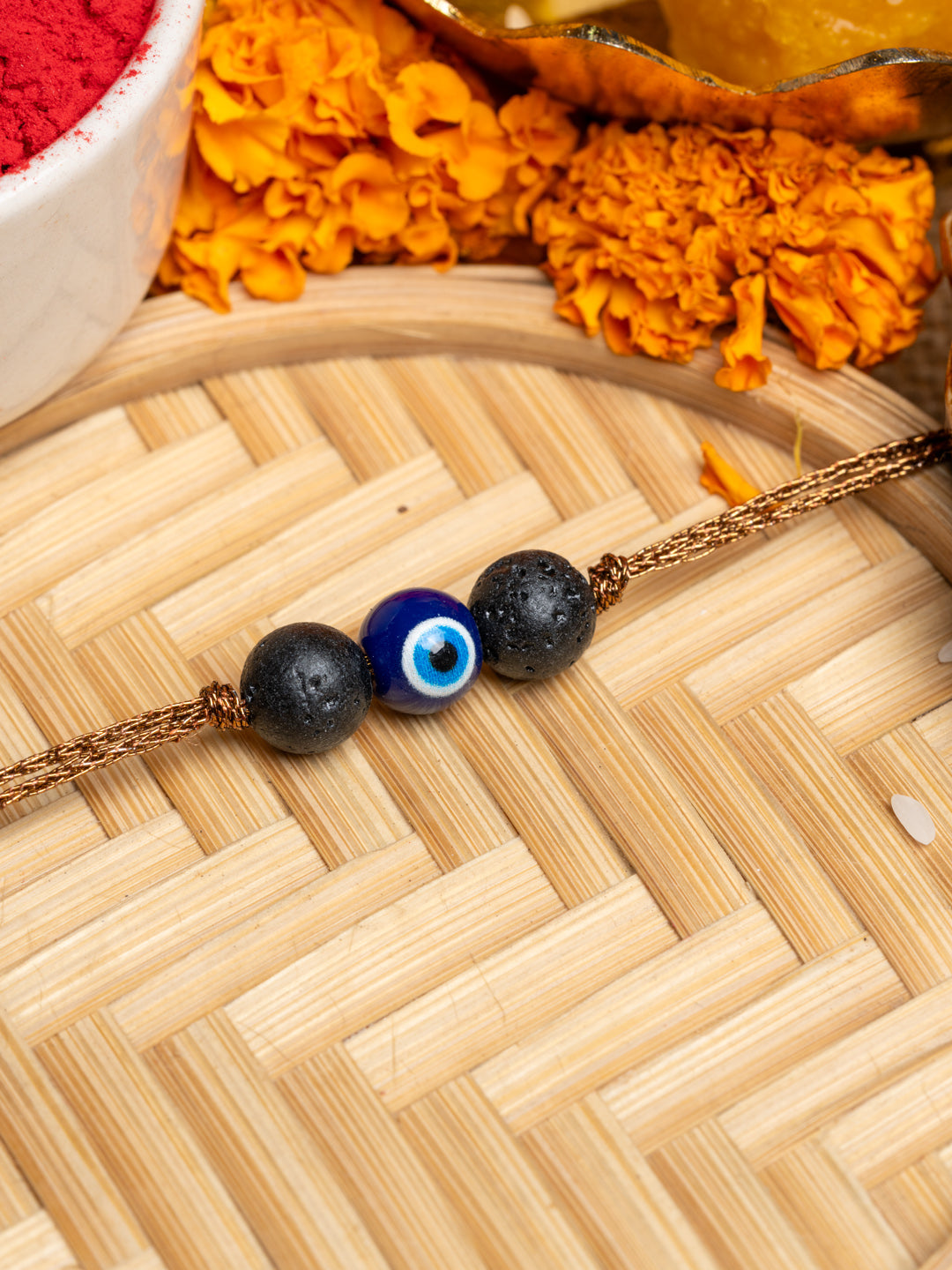 LOOK AND ADORN evil eye rakhi with blue bead and black stones on golden thread