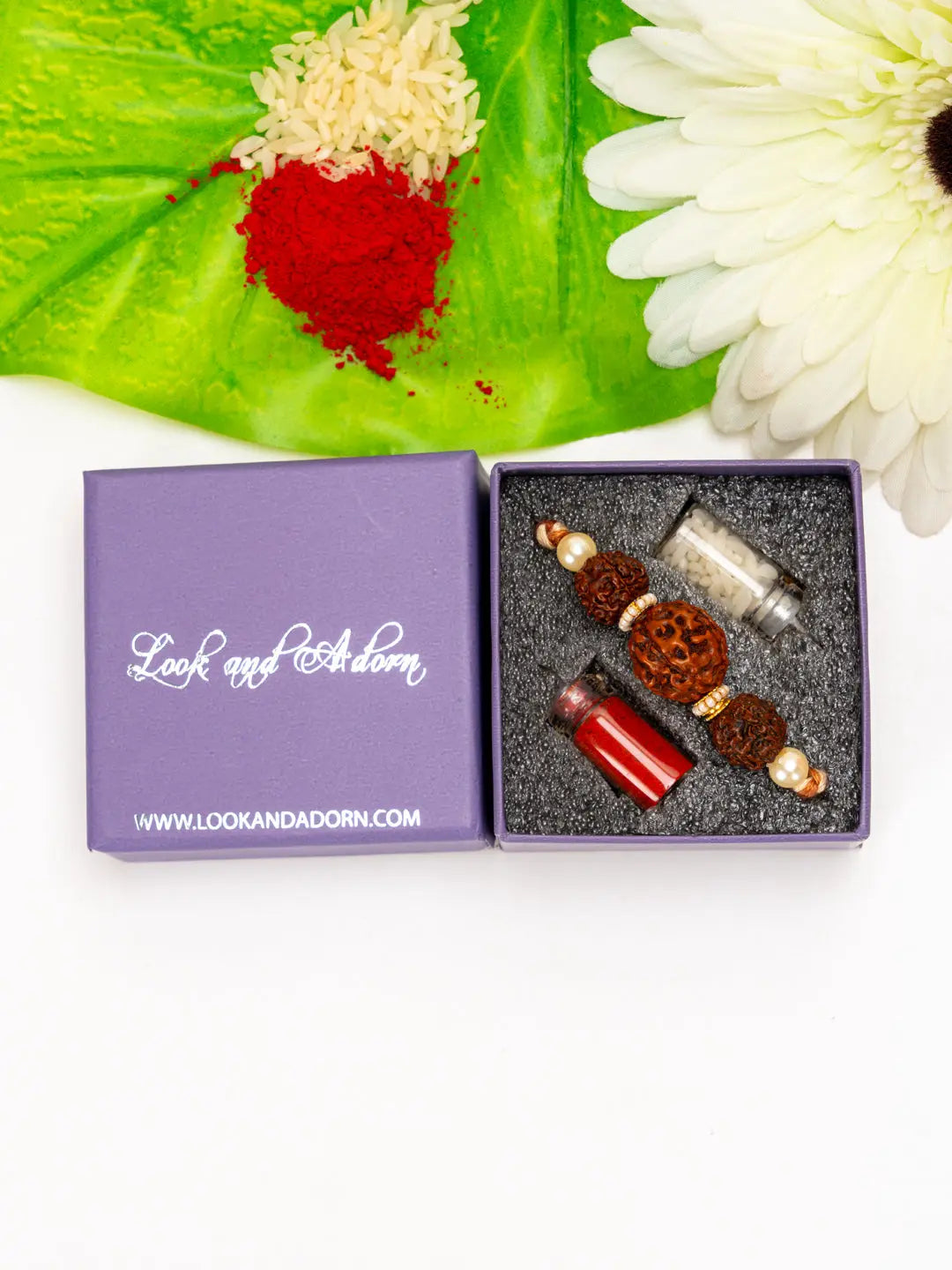 LOOK AND ADORN rudraksh rakhi with beads and small jars in a purple gift box on green leaf background