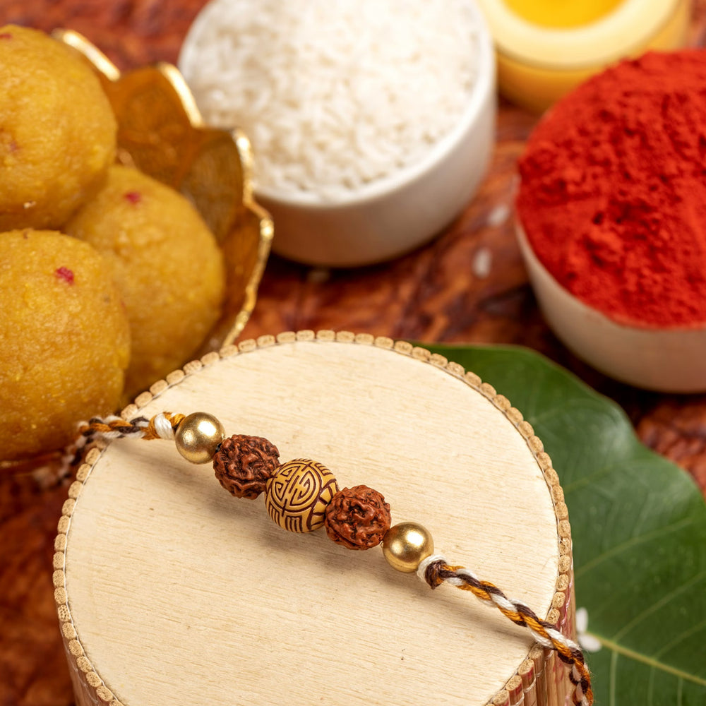 LOOK AND ADORN rudraksh rakhi displayed with traditional Indian sweets, rice, and kumkum powder for festive celebration