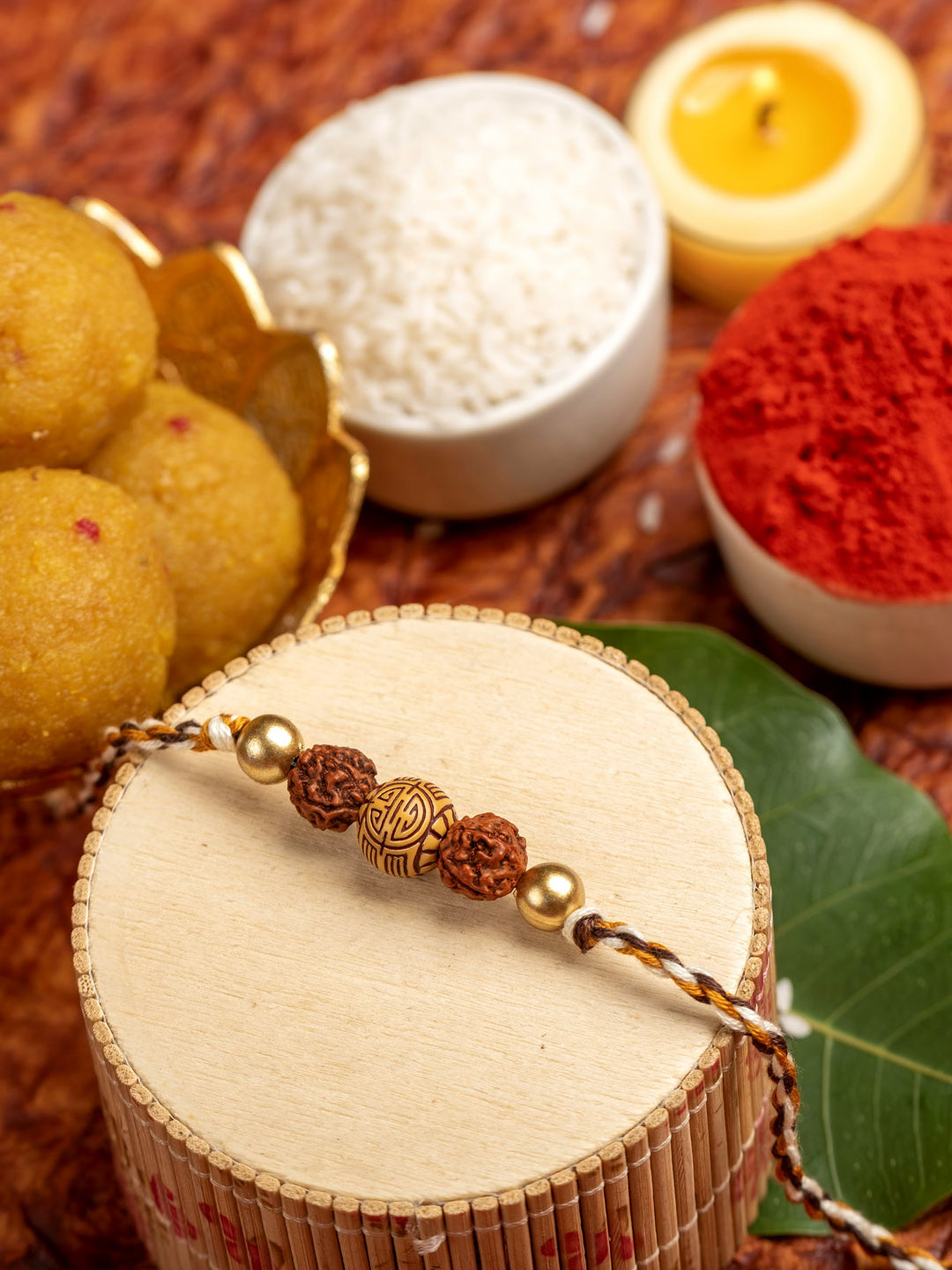LOOK AND ADORN rudraksh rakhi displayed with traditional Indian sweets, rice, and kumkum powder for festive celebration