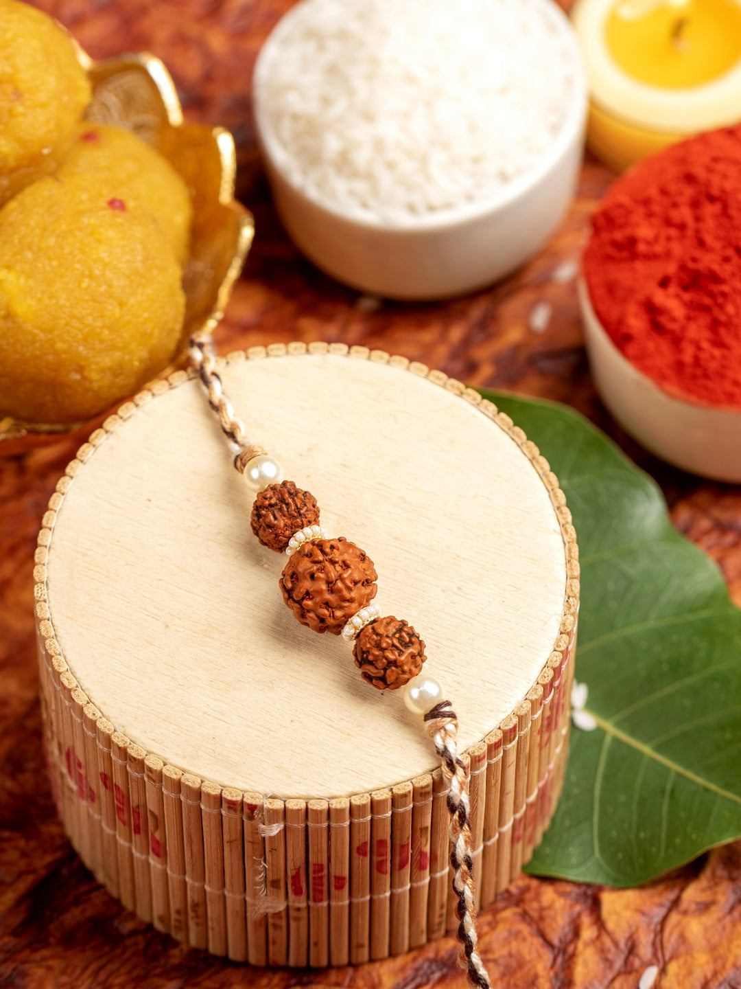 LOOK AND ADORN rudraksh rakhi with three rudraksh beads and pearls on decorative wooden stand