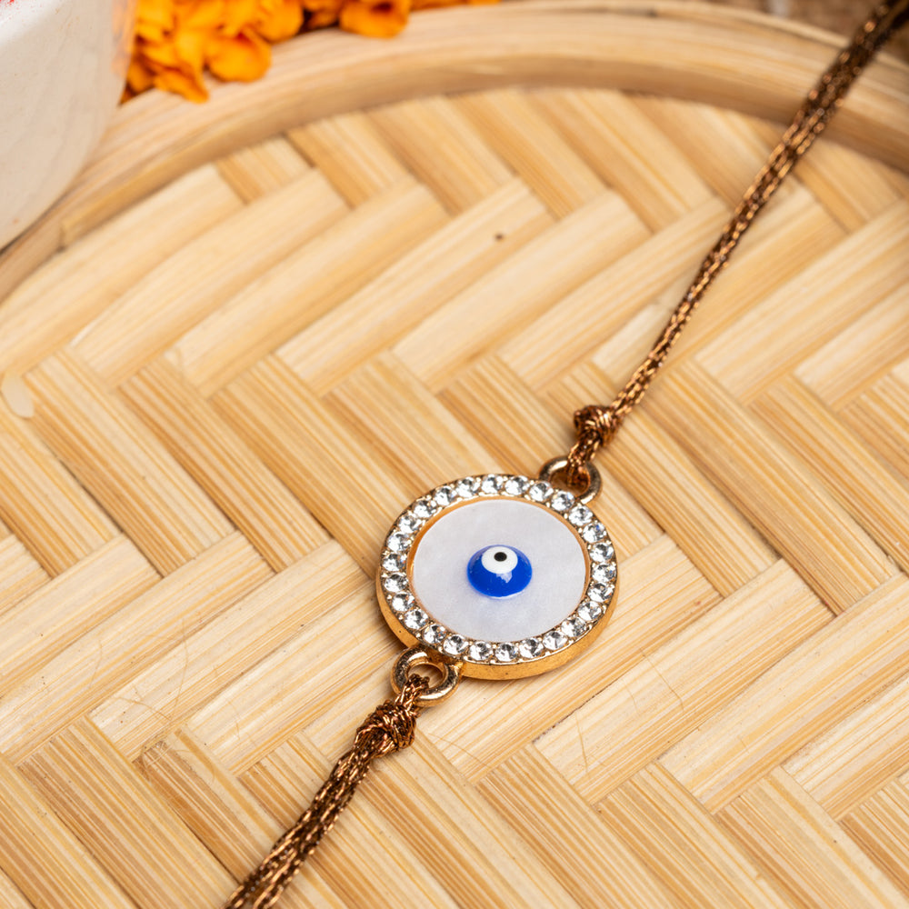 LOOK AND ADORN evil eye rakhi with a blue eye charm surrounded by crystals on a golden chain