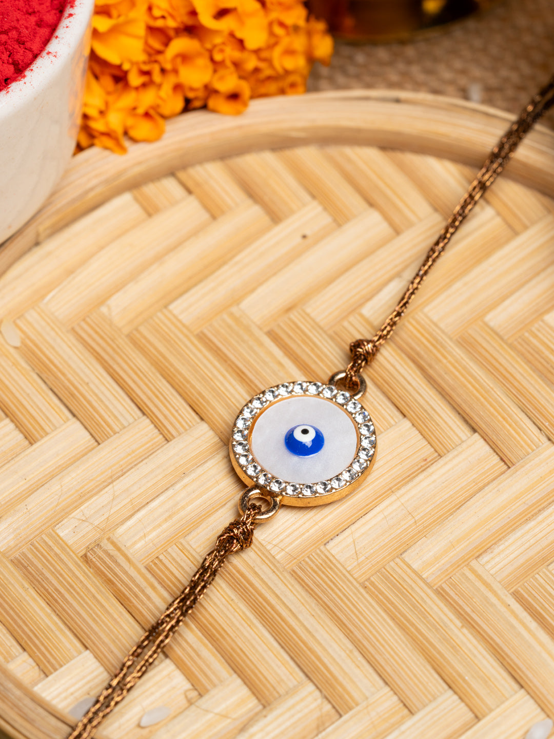 LOOK AND ADORN evil eye rakhi with a blue eye charm surrounded by crystals on a golden chain