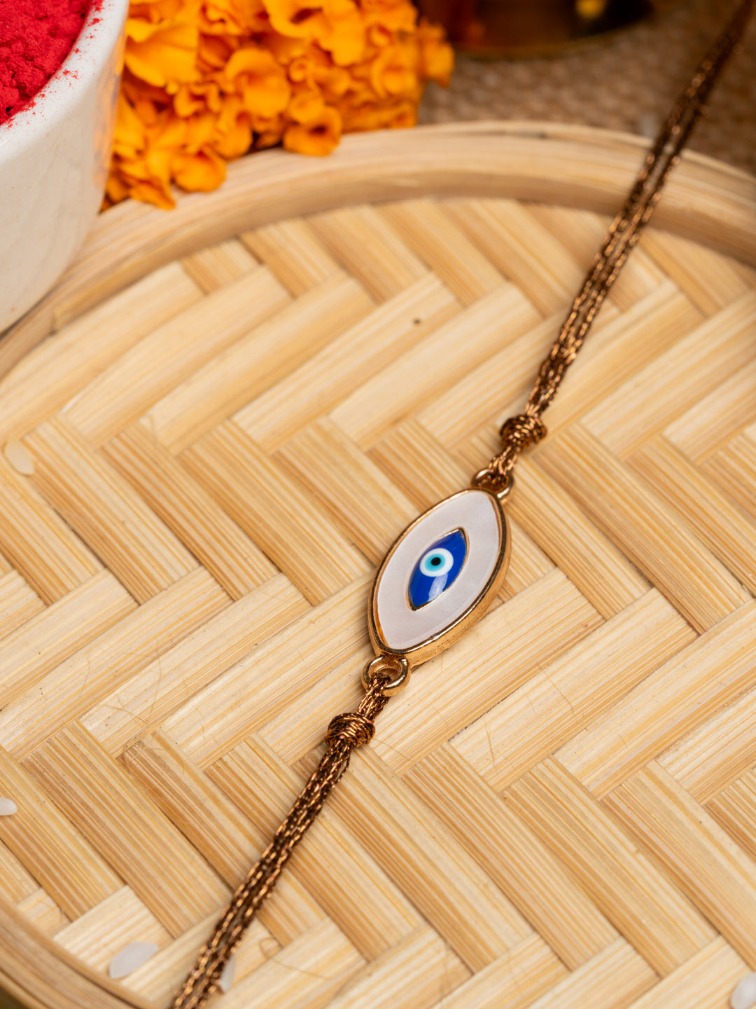 LOOK AND ADORN evil eye rakhi with blue and white charm on a brown braided thread