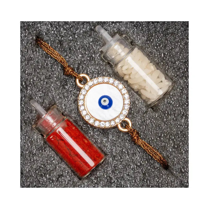 LOOK AND ADORN evil eye rakhi with white and red powder containers on black textured background