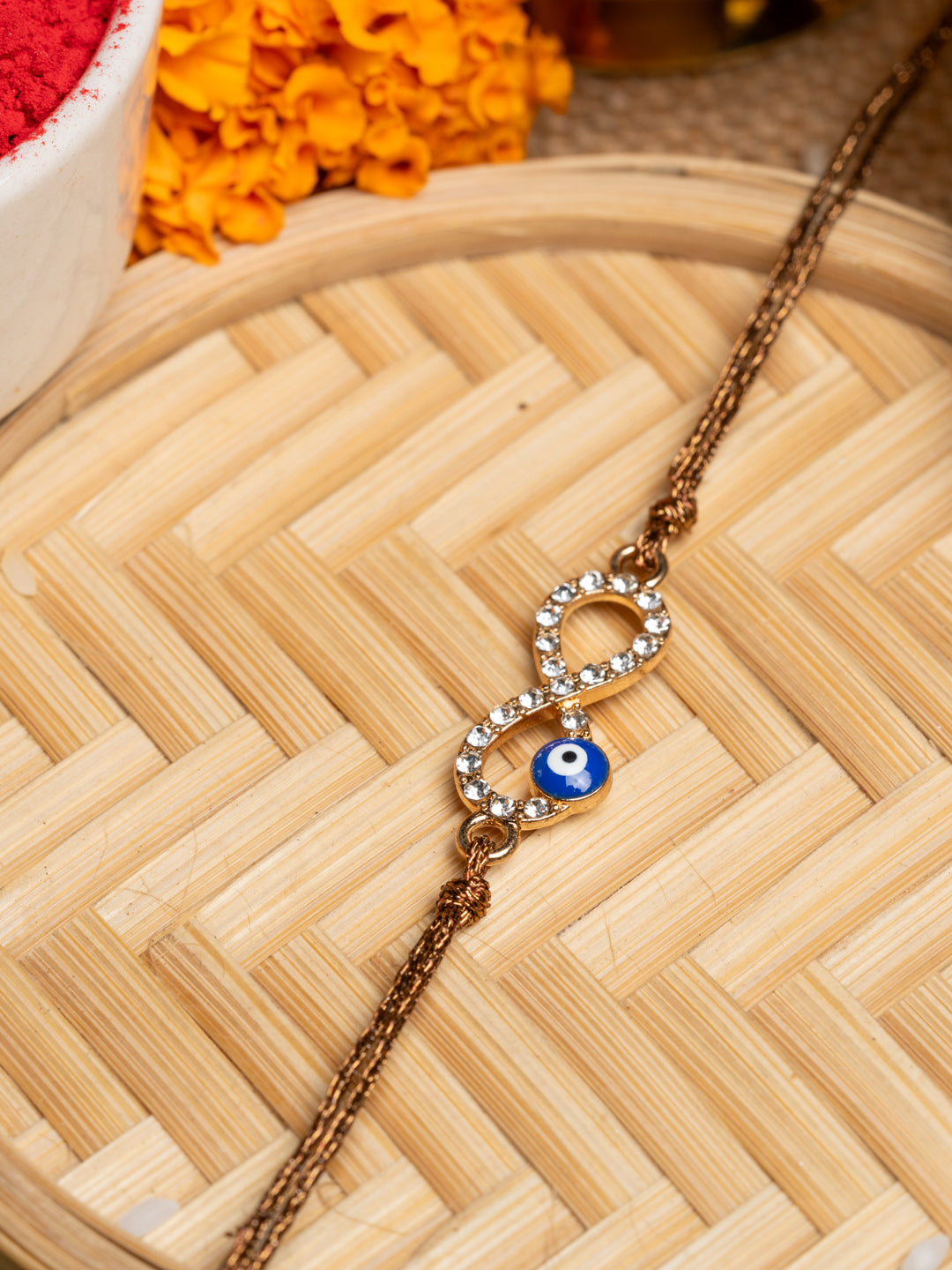 LOOK AND ADORN evil eye rakhi with crystal-studded infinity symbol and blue evil eye charm