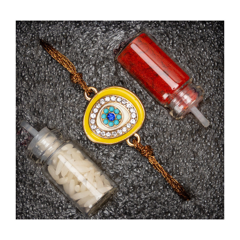 LOOK AND ADORN evil eye rakhi with blue stones and golden thread on textured background