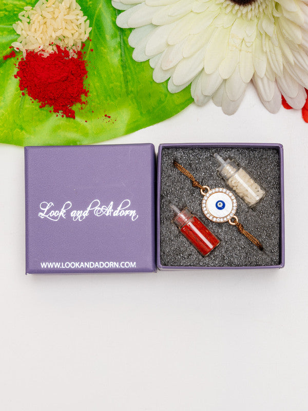 LOOK AND ADORN evil eye rakhi in a purple gift box with red and white powders and a white flower