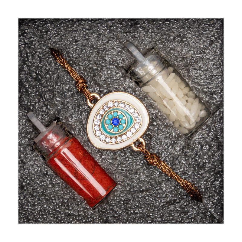 LOOK AND ADORN evil eye rakhi with blue and white stones on golden thread with red and white containers