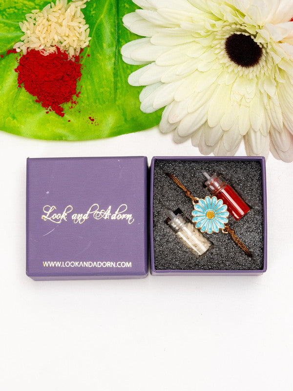 Floral rakhi with blue flower design in Look and Adorn purple gift box with red and white powders and flower