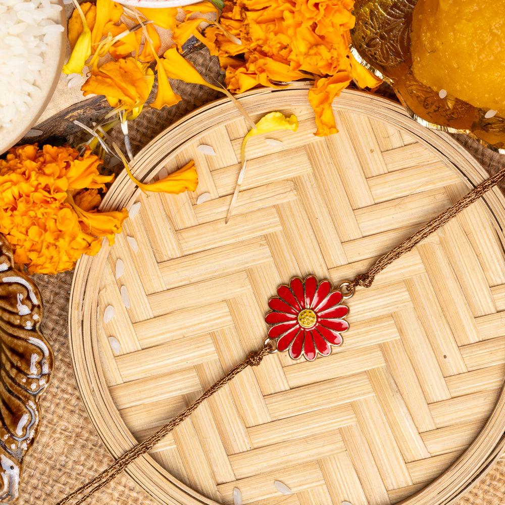 LOOK AND ADORN floral rakhi with red flower design on woven bamboo plate surrounded by marigold flowers and sweets