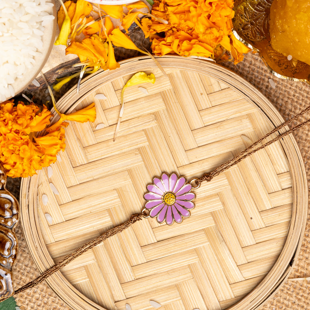 LOOK AND ADORN floral rakhi with purple flower design placed on woven tray with marigold flowers and traditional items