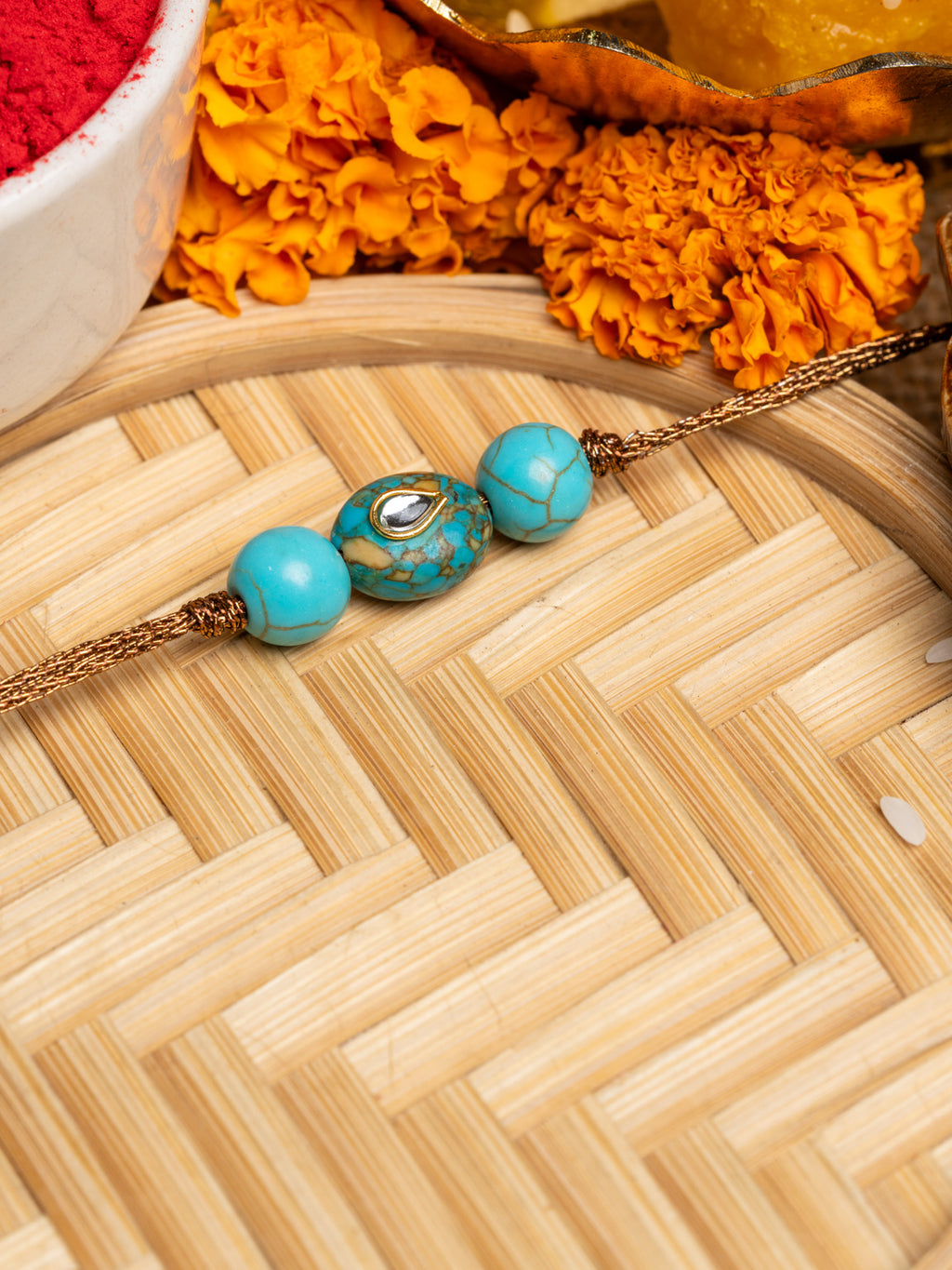 LOOK AND ADORN kundan rakhi with turquoise beads and gold thread on wooden tray with marigold flowers