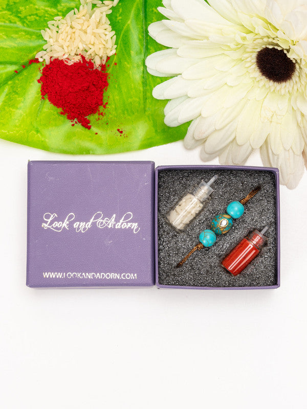 Kundan rakhi with turquoise beads in a purple Look and Adorn gift box with rice and red powder