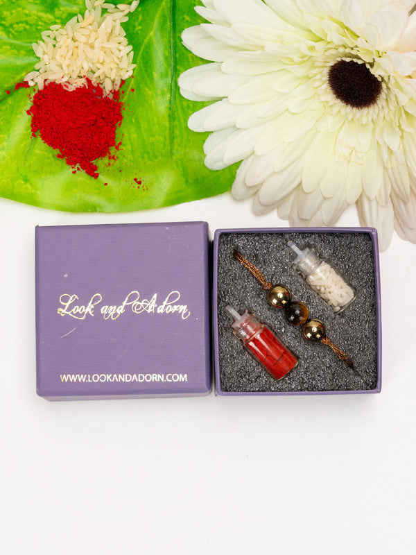 LOOK AND ADORN tiger eye rakhi with decorative beads in purple gift box with rice and red powder on green leaf