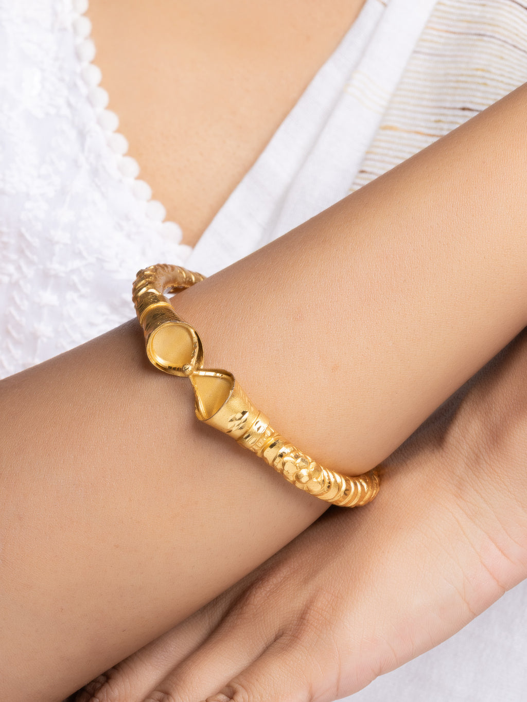 LOOK AND ADORN gold plated bangle with textured twisted design on model wrist wearing white top