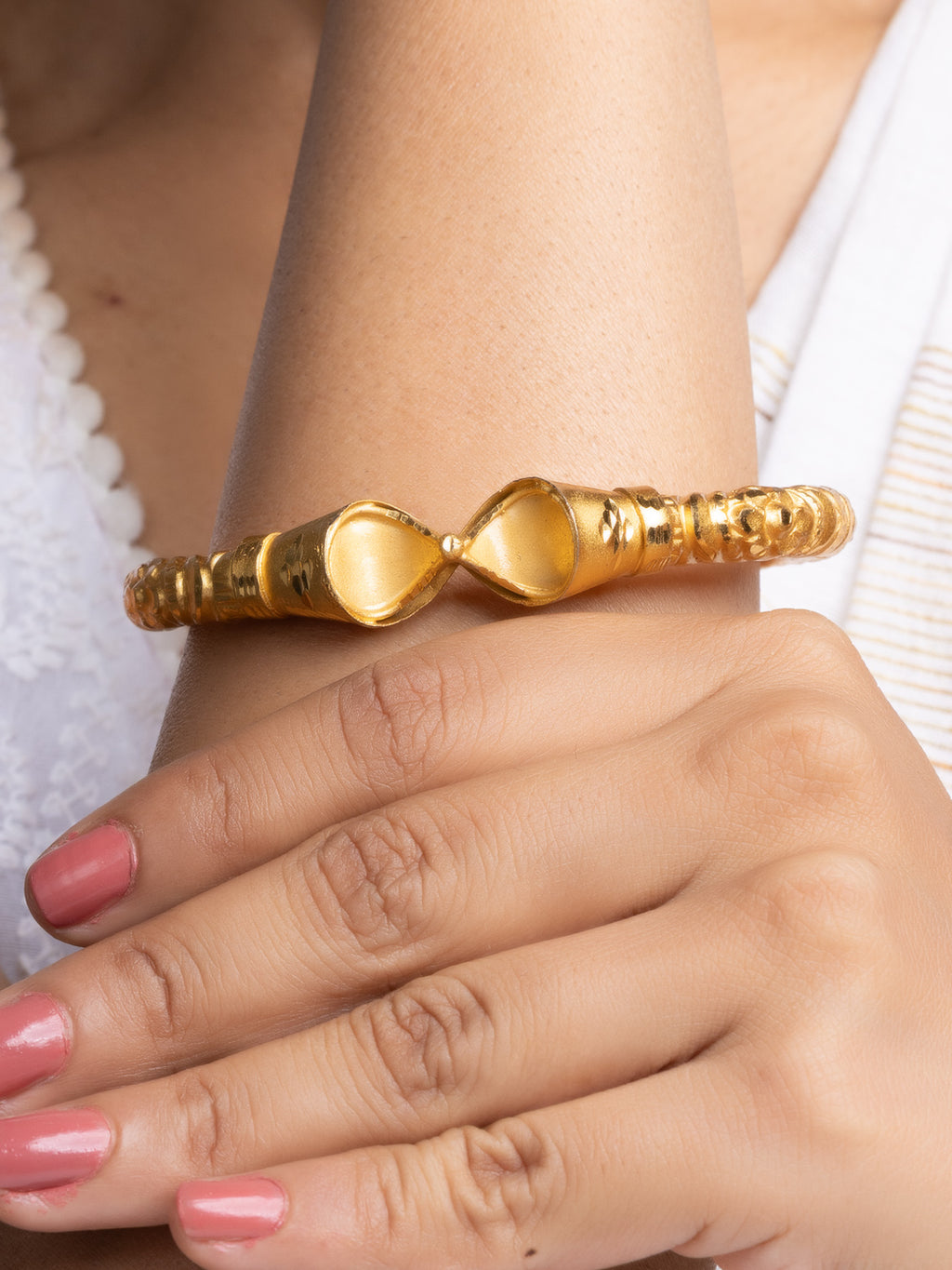LOOK AND ADORN gold plated bangle cuff with textured band and polished teardrop ends on model wrist