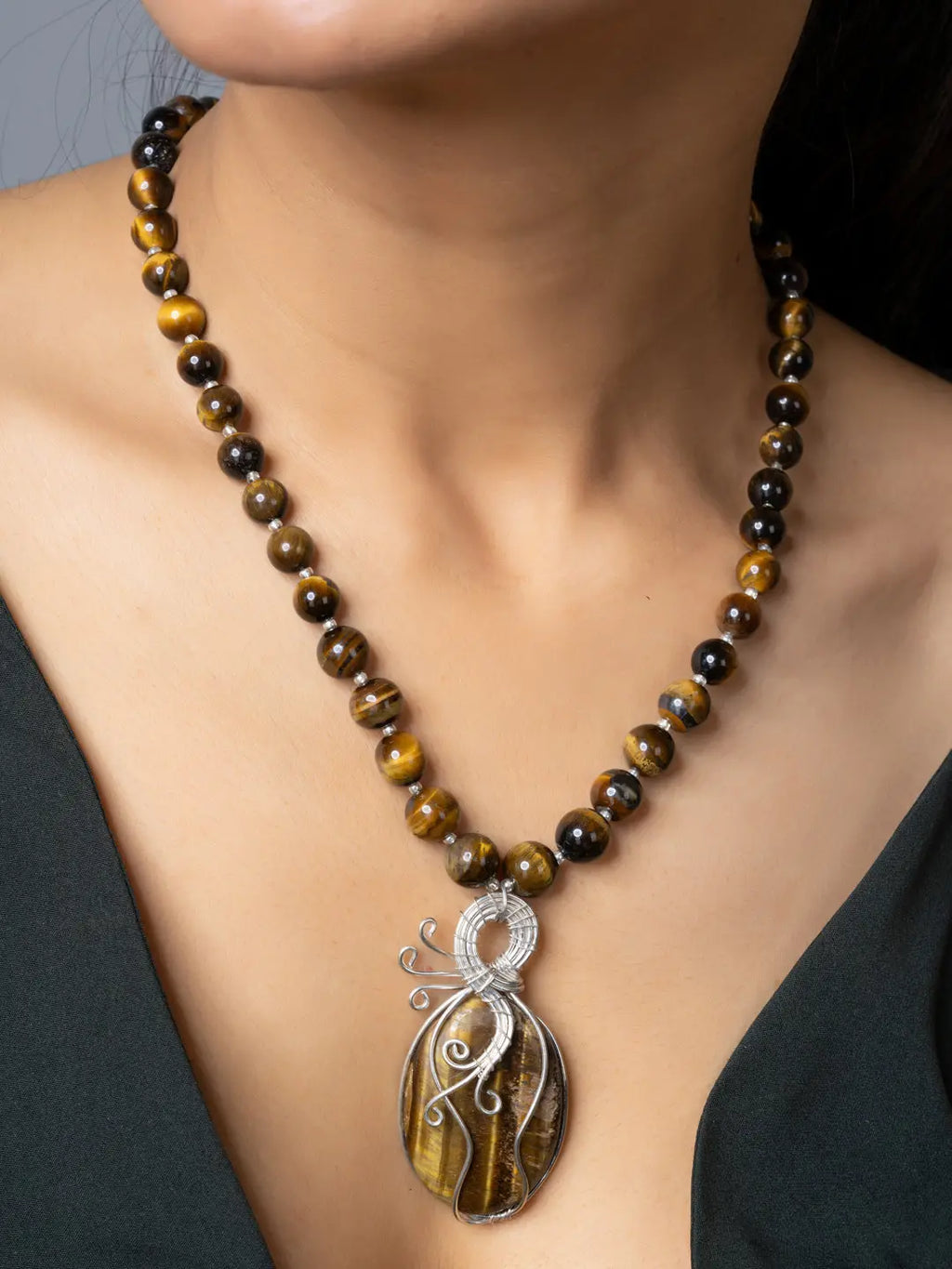 Handmade tiger eye necklace with round polished beads and a wire-wrapped tiger eye pendant worn on a woman