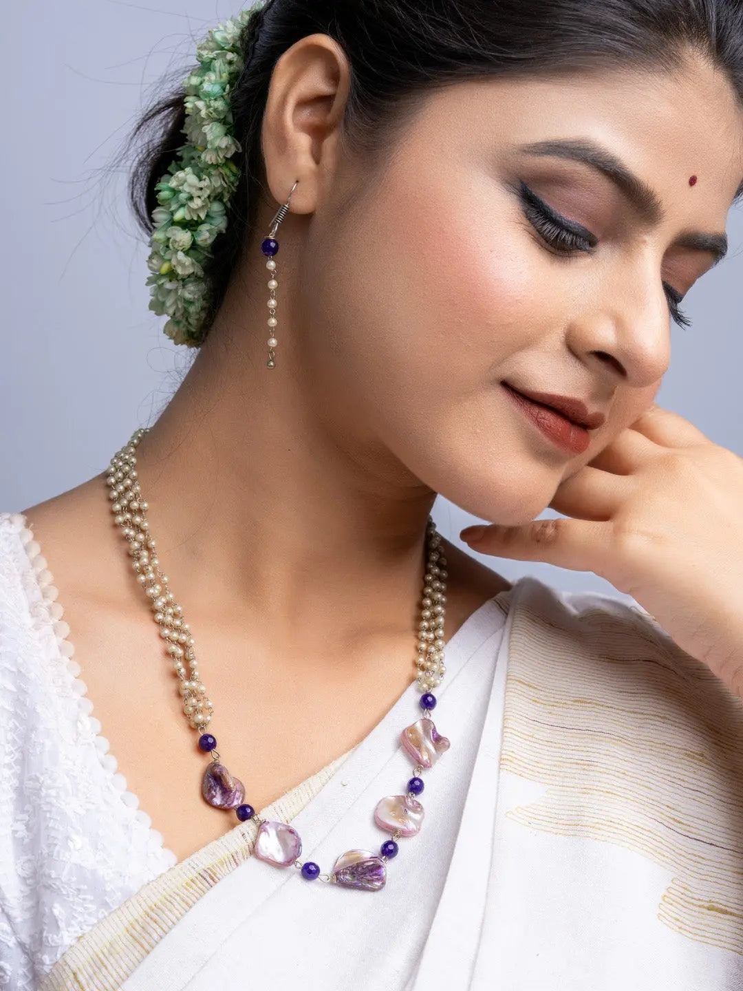 Elegant mother of pearl necklace set worn by woman in traditional white attire with floral hair accessory