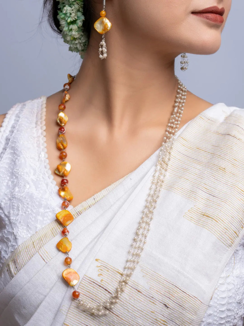 Elegant mother of pearl necklace set with gold and pearl beads worn with traditional white saree