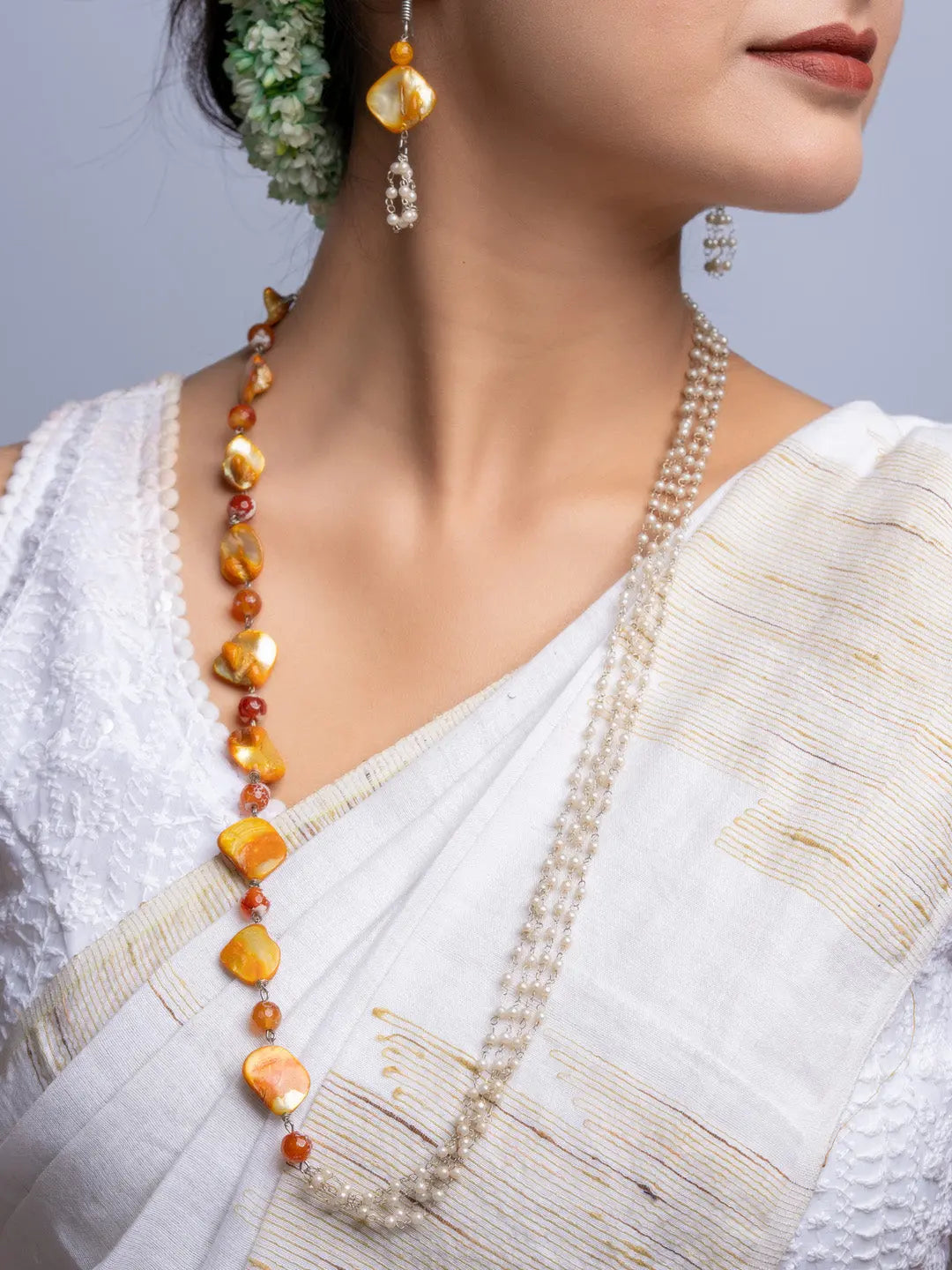 Elegant mother of pearl necklace set with gold and pearl beads worn with traditional white saree