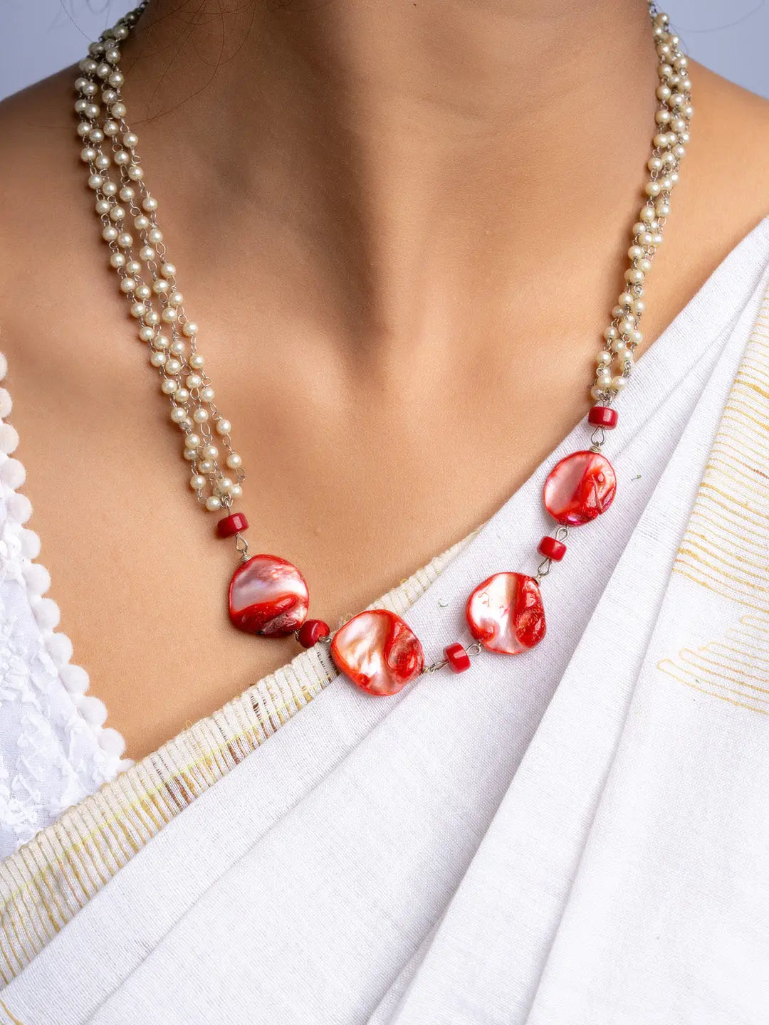 Handmade mother of pearl necklace set with red and white beads worn with traditional white saree