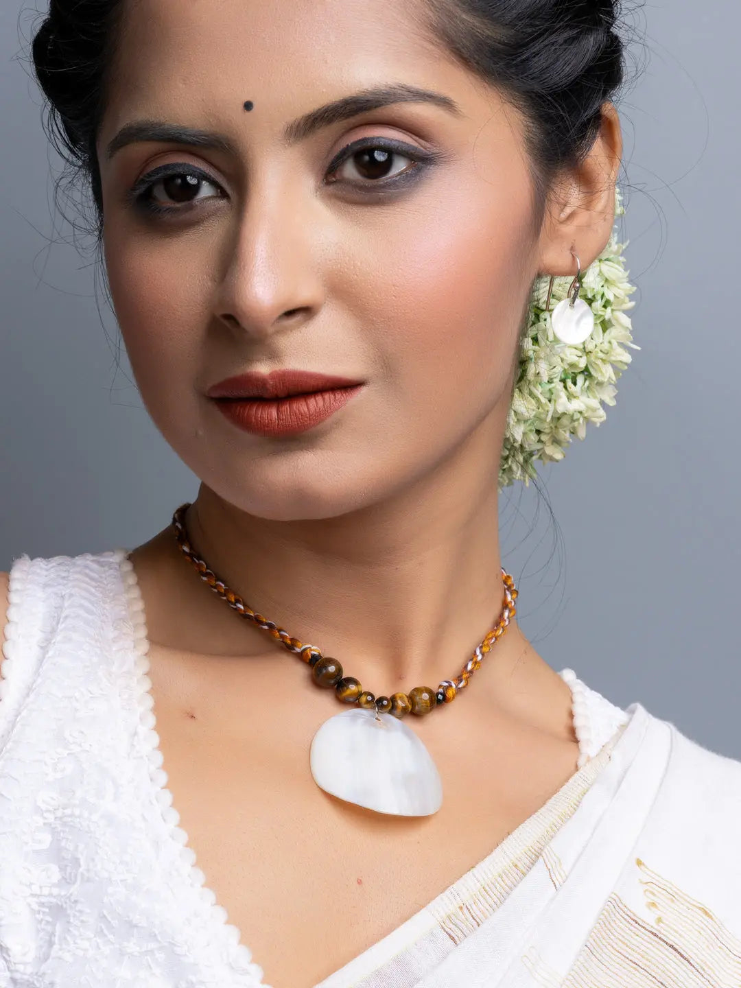 Handmade mother of pearl necklace set with brown beads worn by woman in white blouse